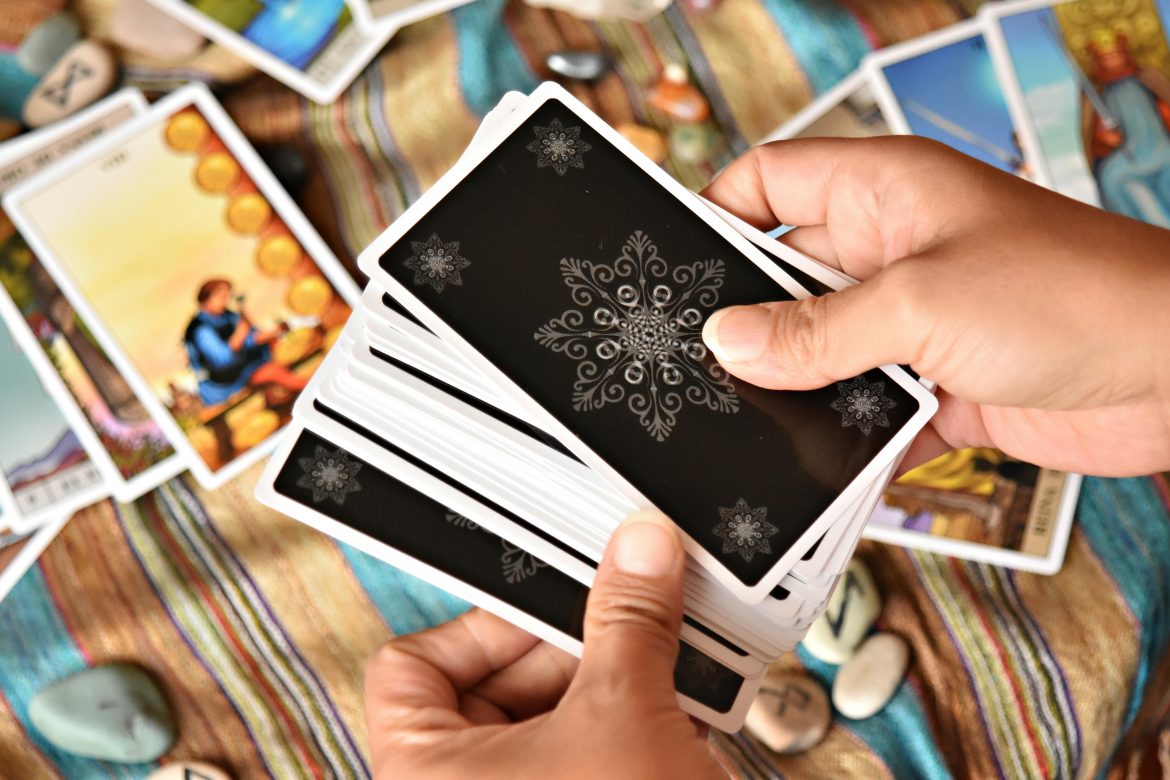 Hands shuffling tarot deck on colorful cloth
