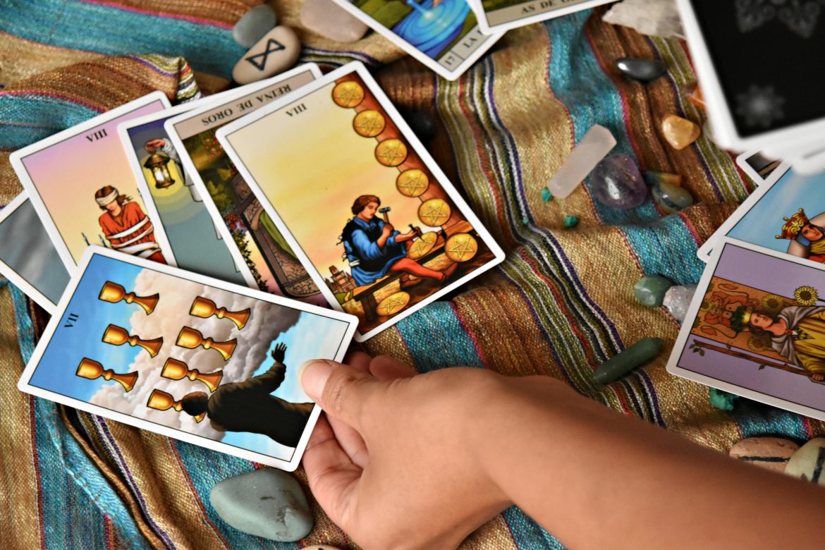 Hand holding tarot card in reading spread