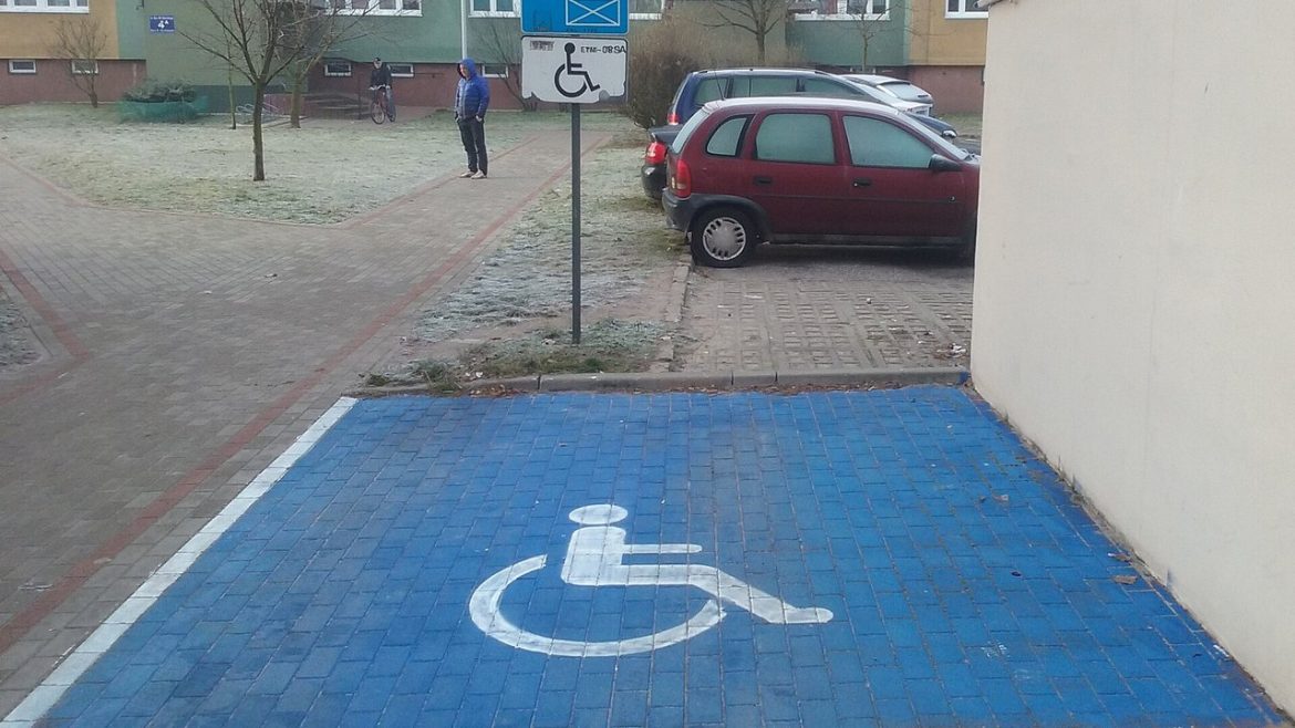 Oznakowane miejsce parkingowe dla osób z niepełnosprawnością na osiedlowym parkingu